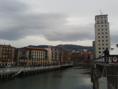 Bilbao is built by a river and with mountains in behind.